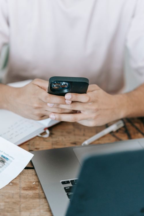 Free High angle anonymous male surfing mobile phone and sitting at desk with modern netbook and papers Stock Photo