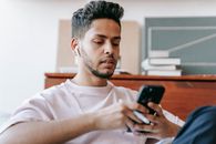 Ethnic man surfing smartphone and sitting in light room