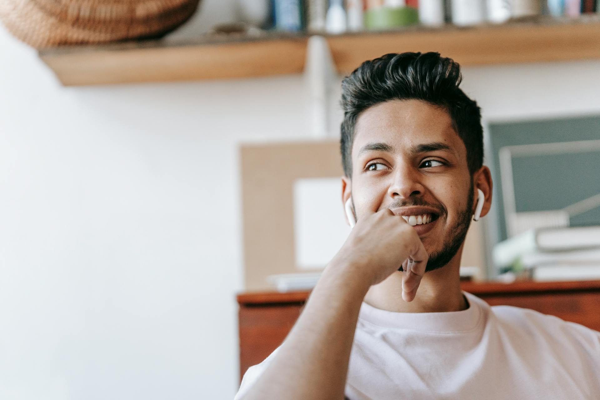 Charismatic young adult listening to music indoors with a satisfied smile, creating a joyful atmosphere.