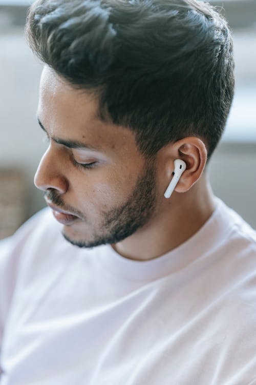 Crop thoughtful man listening to music in earbuds