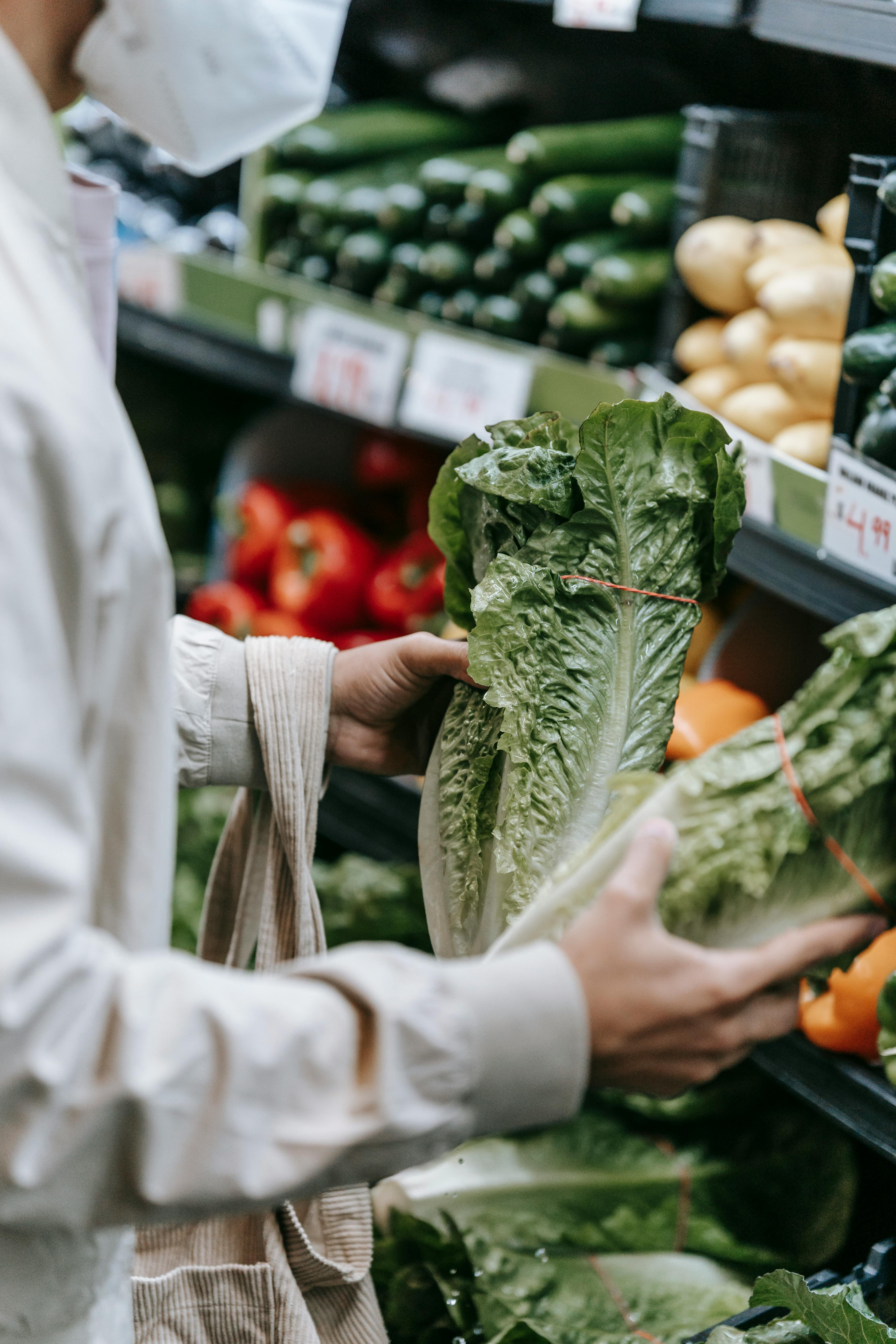 unrecognizable customer in medical mask with lettuce in supermarket