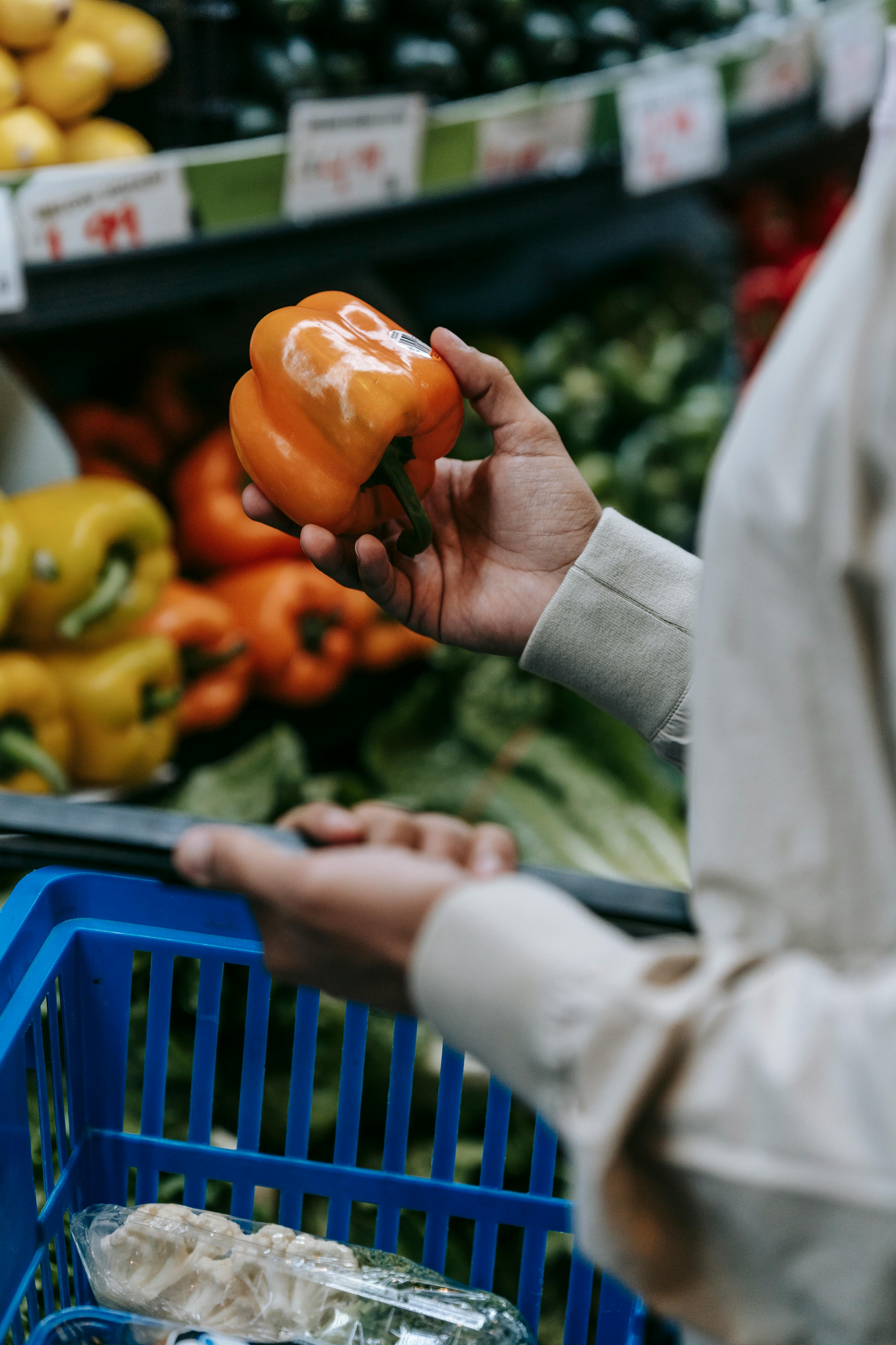 anonymous buyer with bell pepper in supermarket