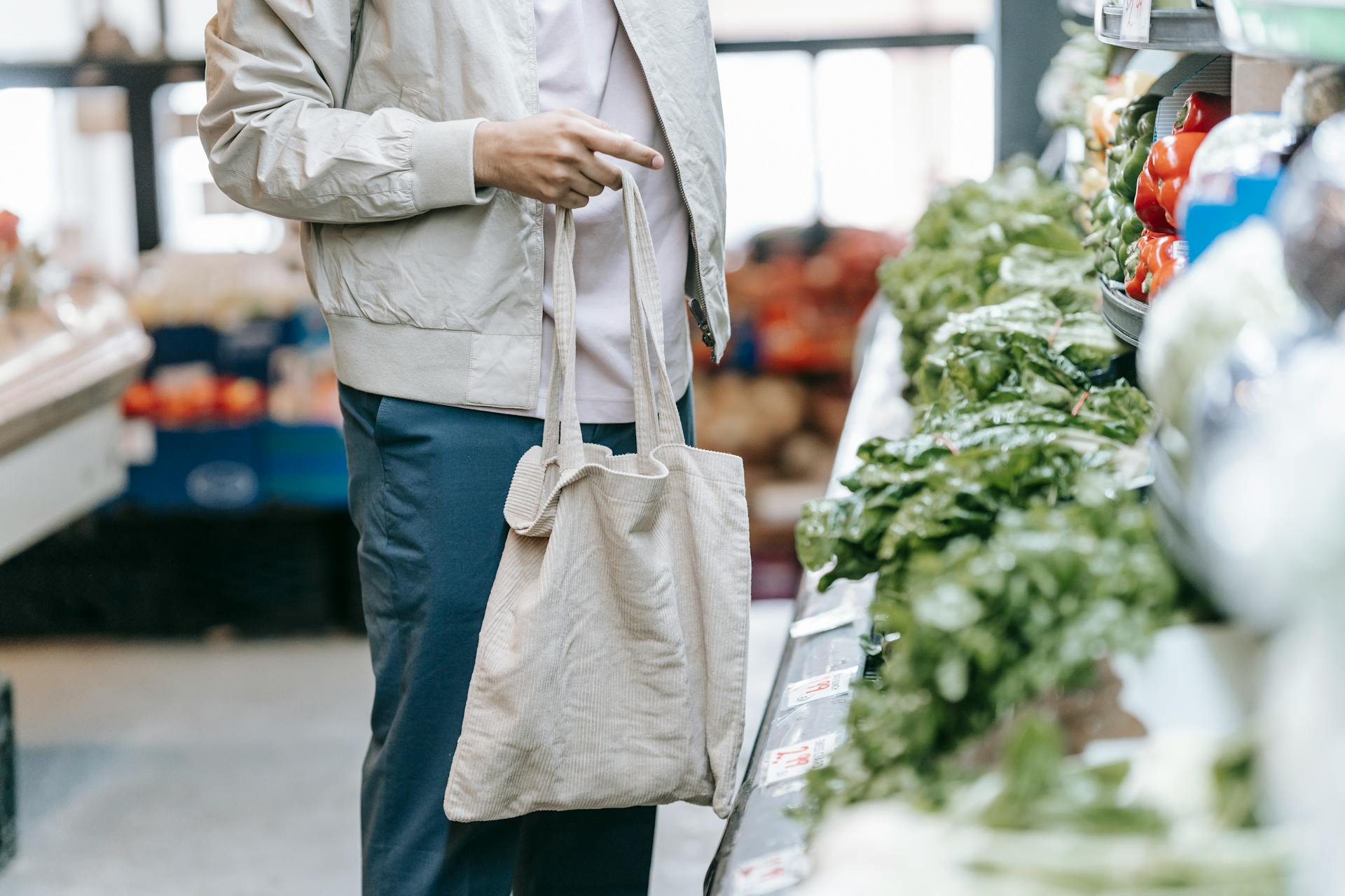 Unrecognizable customer near greens in supermarket