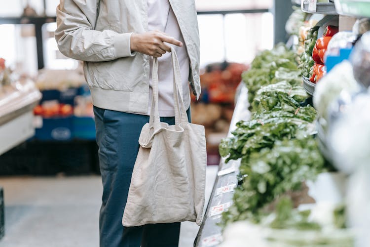 Unrecognizable Customer Near Greens In Supermarket