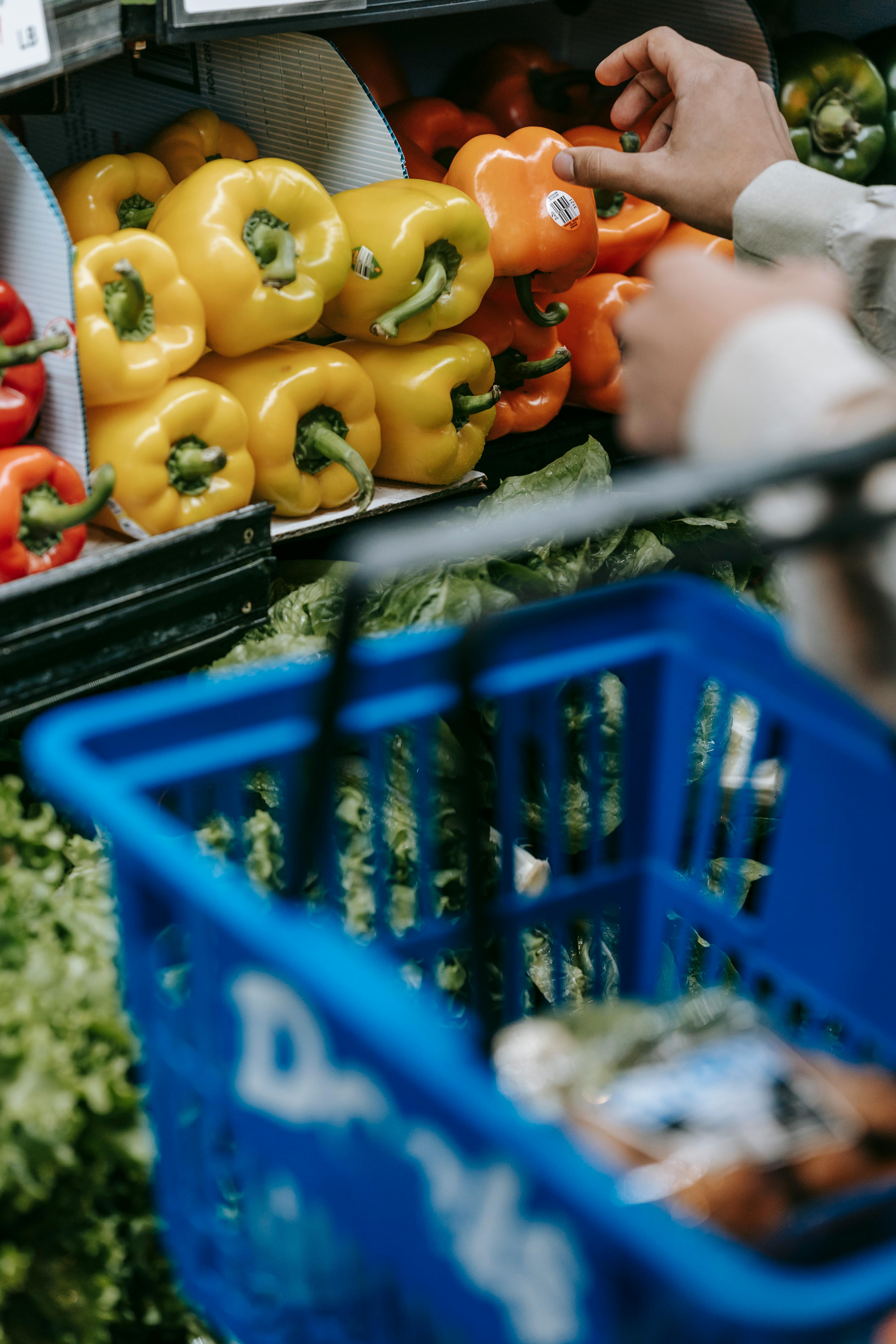 anonymous customer with shopping basket picking bell peppers