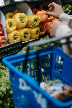 Shopper picking vibrant bell peppers from supermarket produce section for healthy cooking.