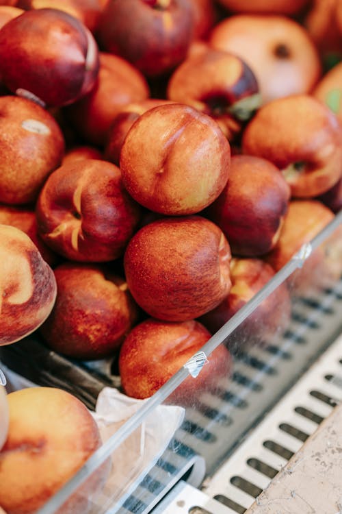 From above of pile of fresh ripe tasty nectarines and peaces in glass containers placed in grocery market