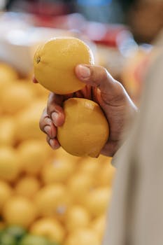 A shopper selects fresh lemons in a bright indoor market setting.