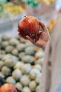 Crop male buyer choosing pomegranate in grocery market