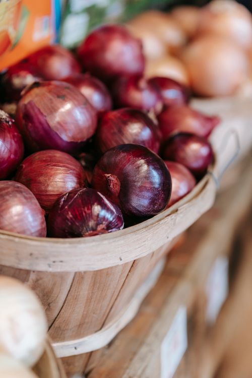 Free From above of ripe fresh red onions in wooden bucket placed on stall in local food market Stock Photo