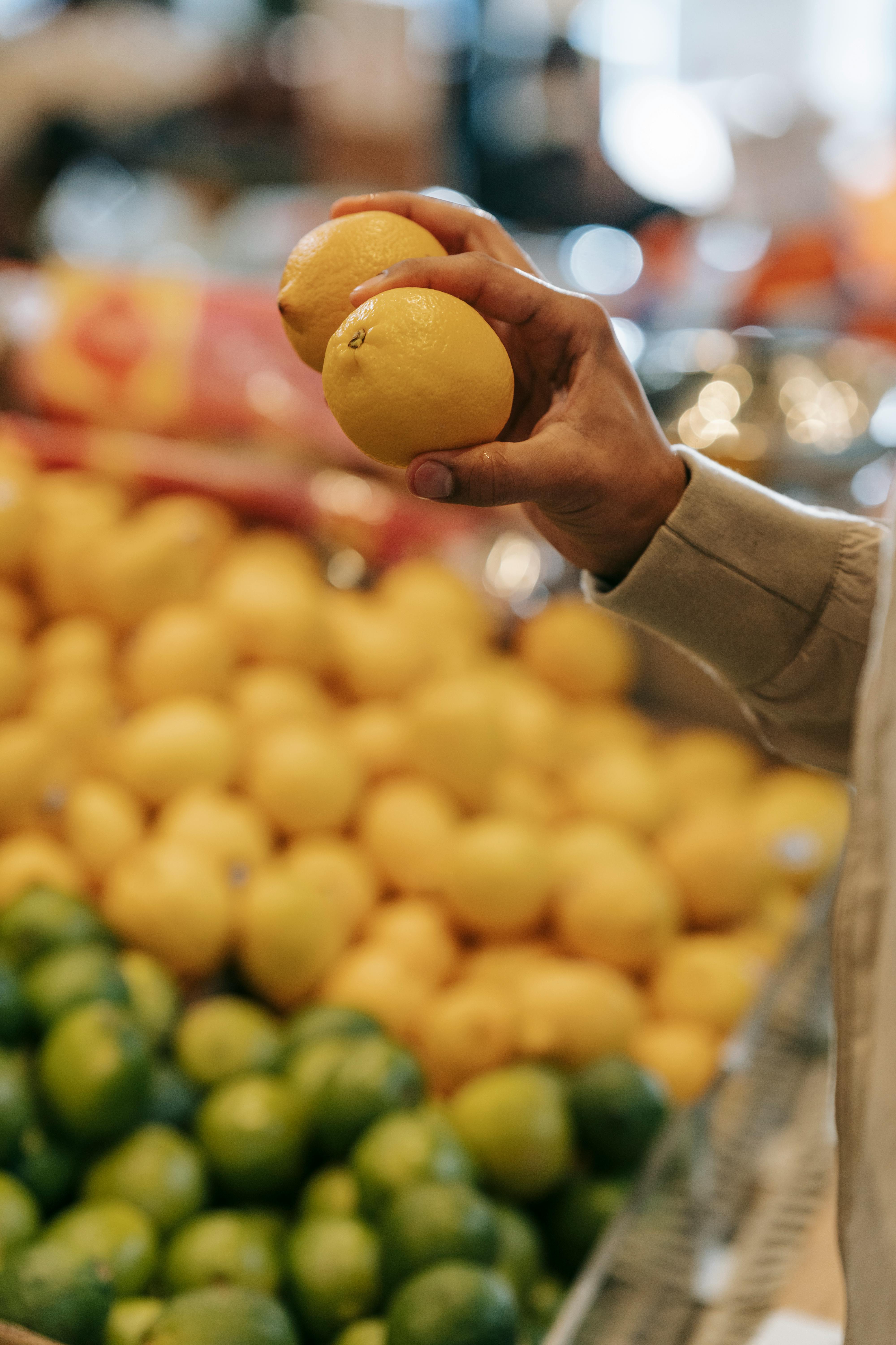 faceless man choosing citruses in supermarket
