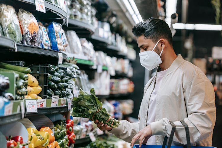 Young Ethnic Guy Buying Bunch Of Fresh Spinach In Supermarket