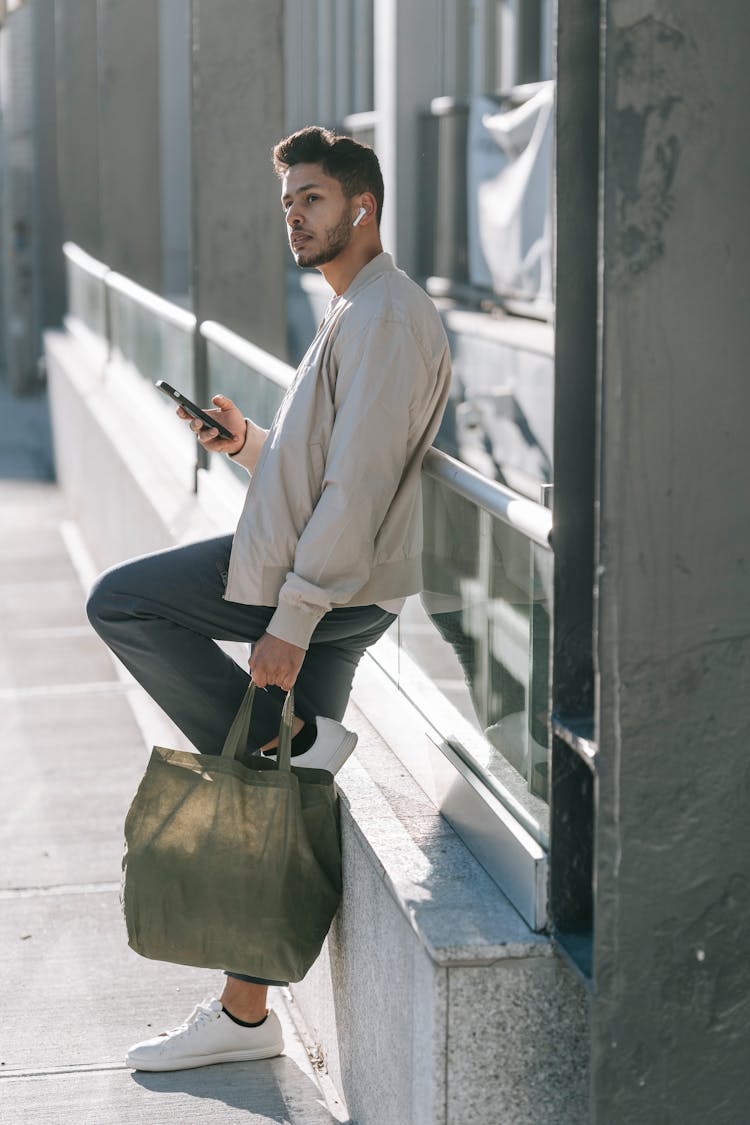 Stylish Indian Man With Smartphone And Eco Bag In City