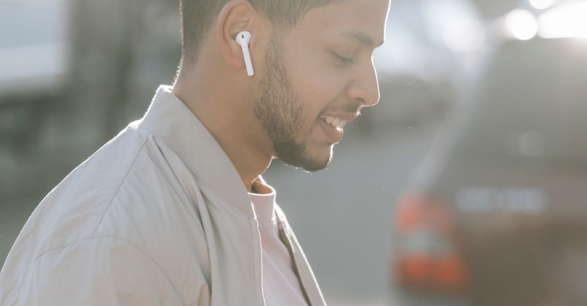 Man Calling Using Earbud Trendy Indian man listening to song from earbud on road · Free Stock Photo