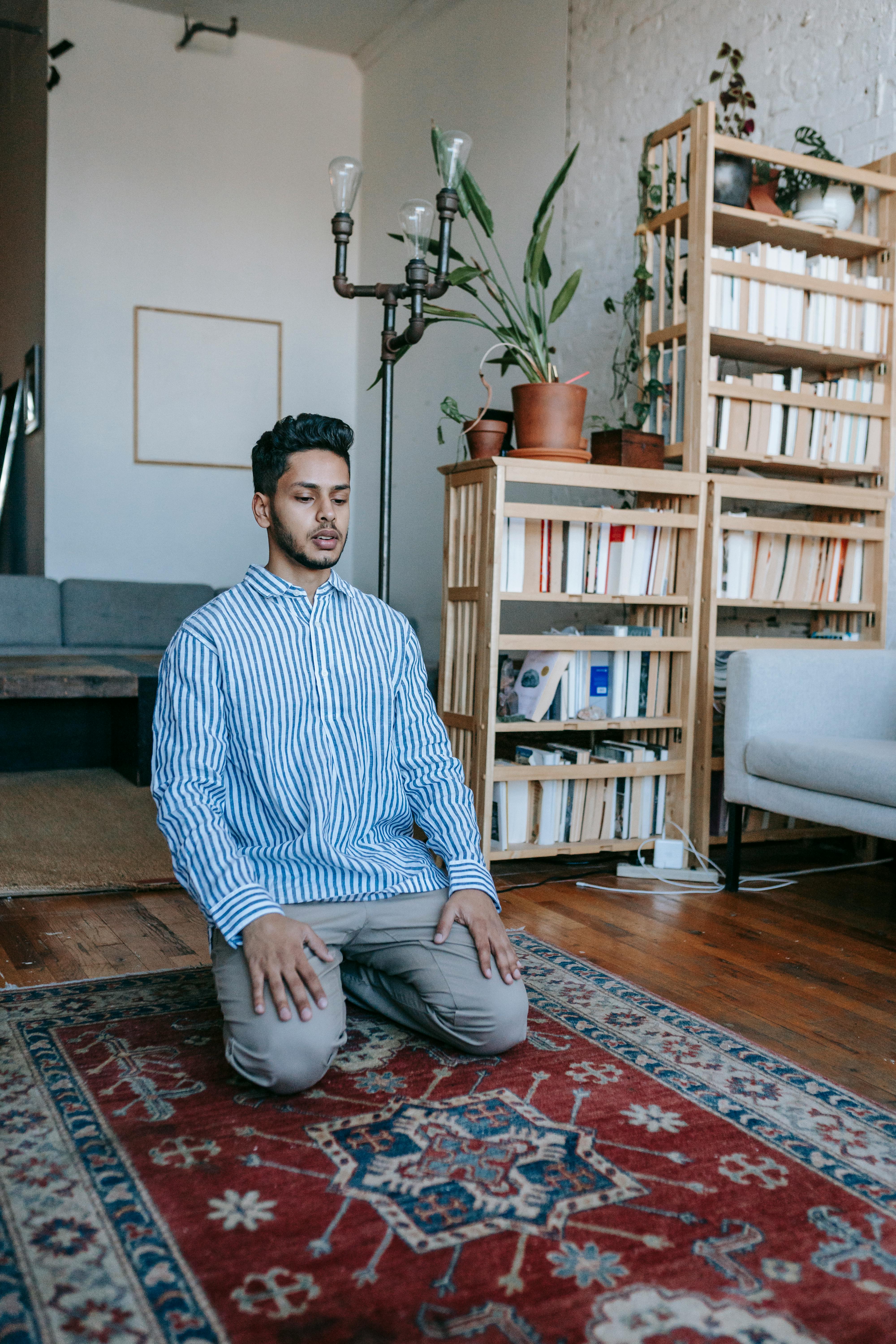 man in blue and white striped dress shirt kneeling on floor