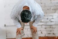 Man in Blue and White Stripe Dress Shirt Bowing Down on Red and Blue Area Rug