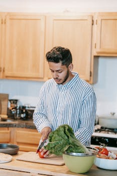 Adult man cutting vegetables on a wooden board in a modern kitchen.
