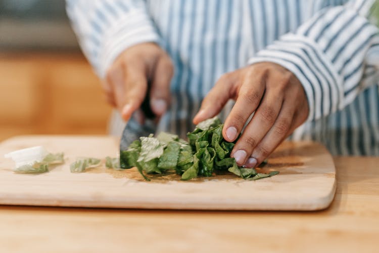 Crop Man Cutting Green Leaves While Preparing Healthy Food In Kitchen