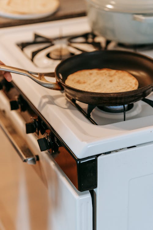From above of traditional Indian chapati flatbread frying in an placed on gas stove in kitchen