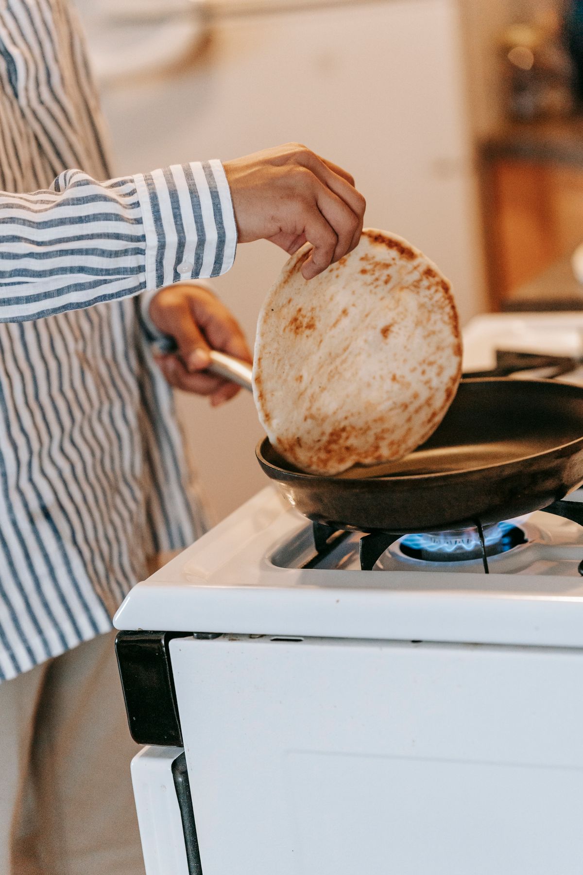 Pancake being warmed and flipped in a frying pan on a kitchen stove