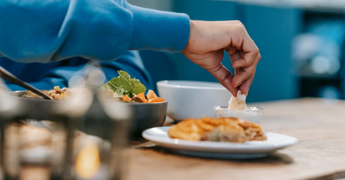 person eating a colorful plate of food with a clock in the background, hands pointing to different meal times