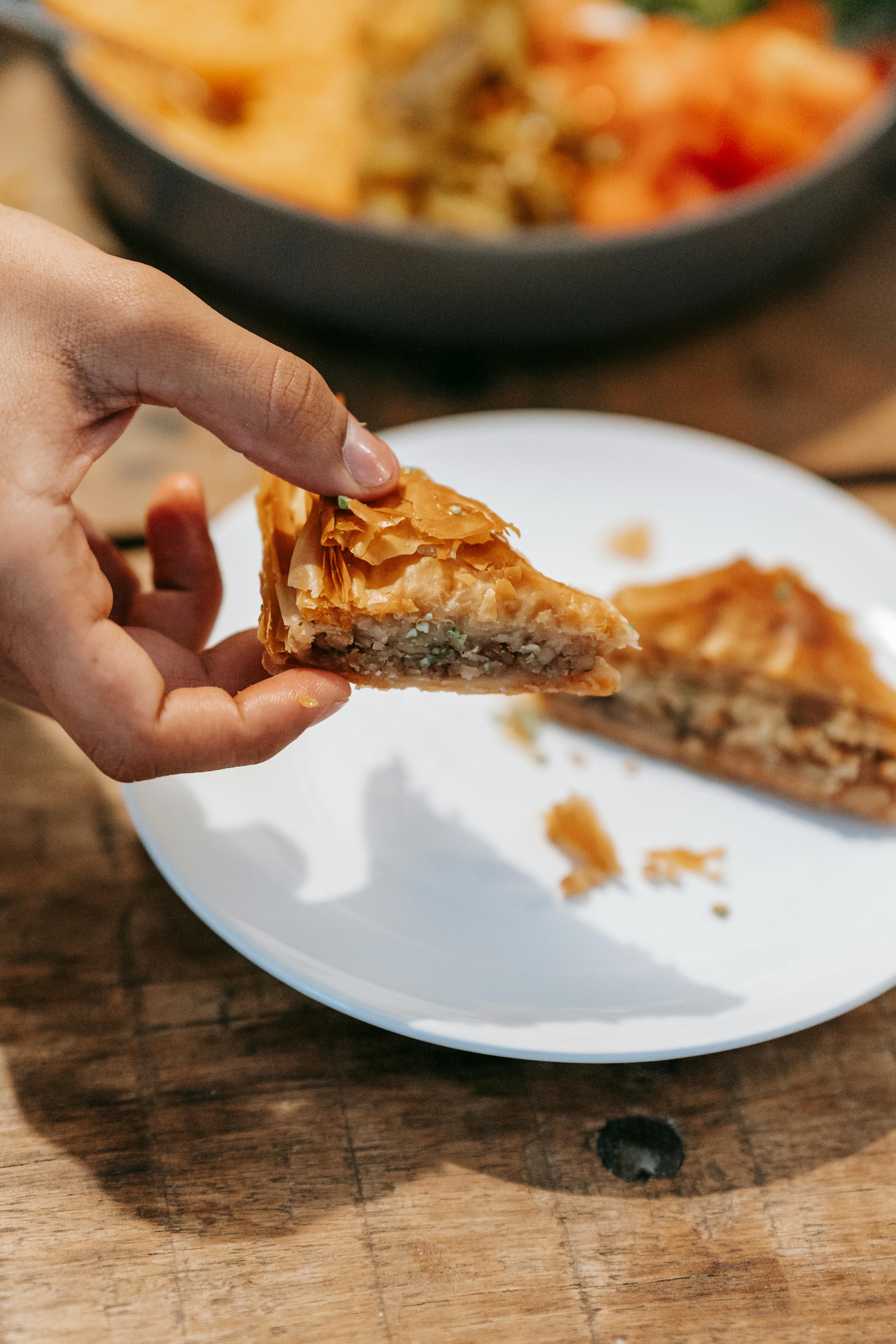 Man showing sweet baklava in hands at table with food · Free Stock Photo