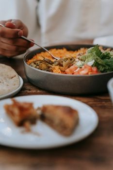 A traditional meal featuring pita bread and vegetables is served on a wooden table, highlighting a Middle Eastern dining experience.