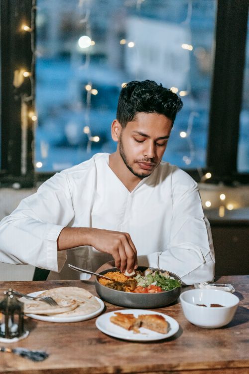 Free Young man savoring a traditional Middle Eastern meal indoors with festive ambiance. Stock Photo