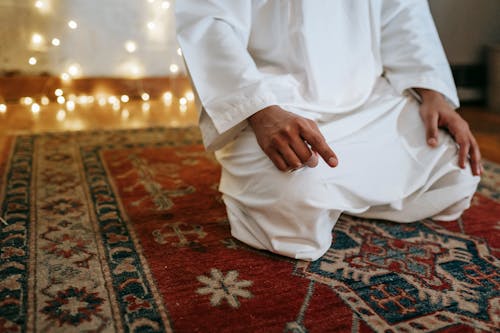 Man in White Thobe Sitting on Red and Brown Area Rug