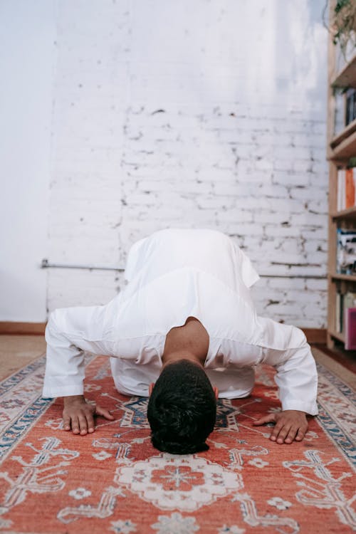 Man in White Thobe Kneeling on Red and Brown Area Rug