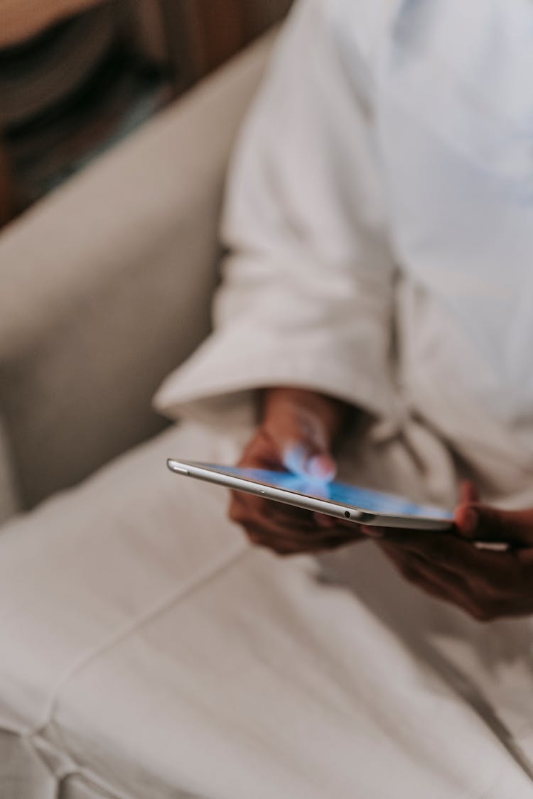 Person In Light Clothes Surfing Tablet In Light Room