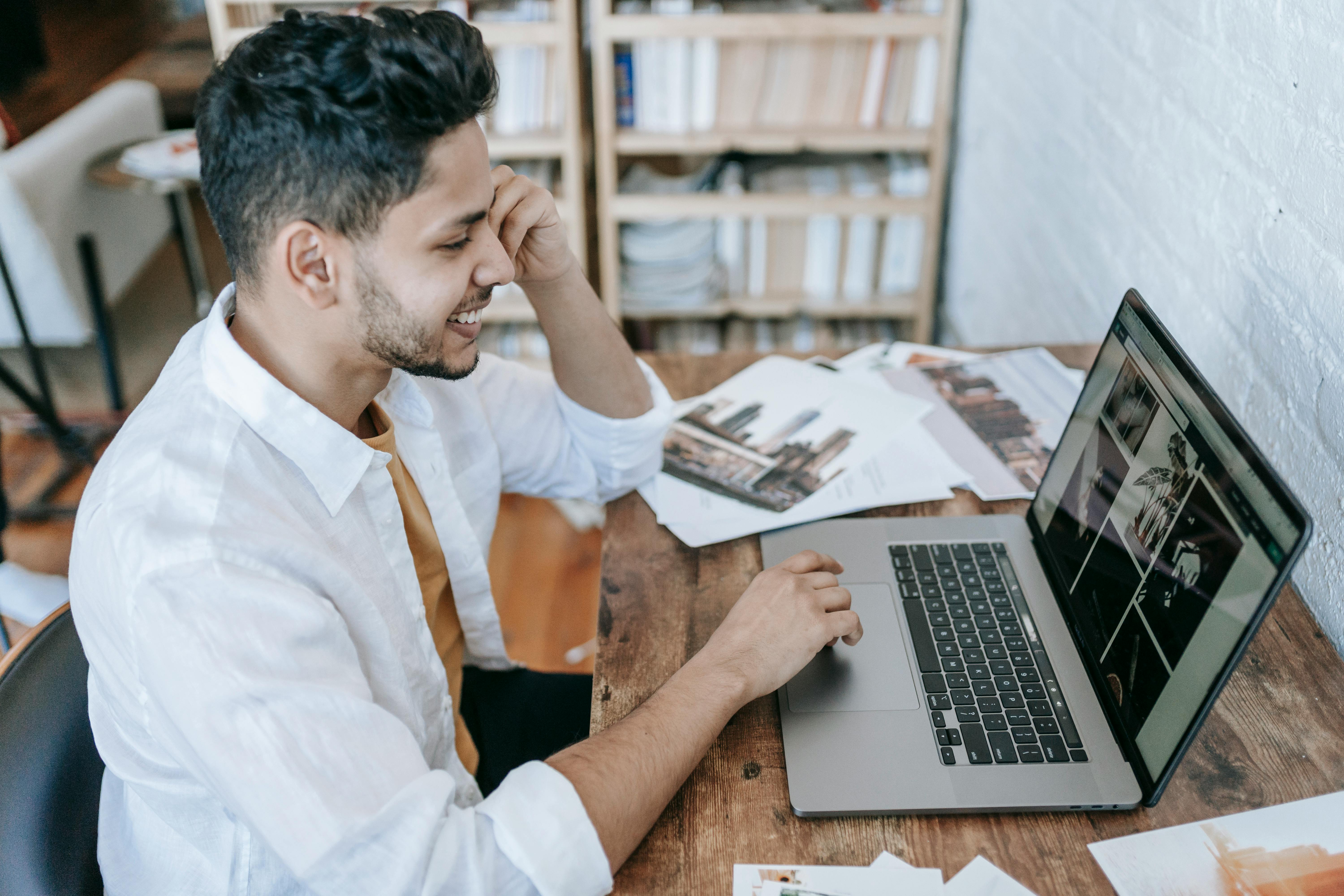 positive ethnic male working on laptop in room