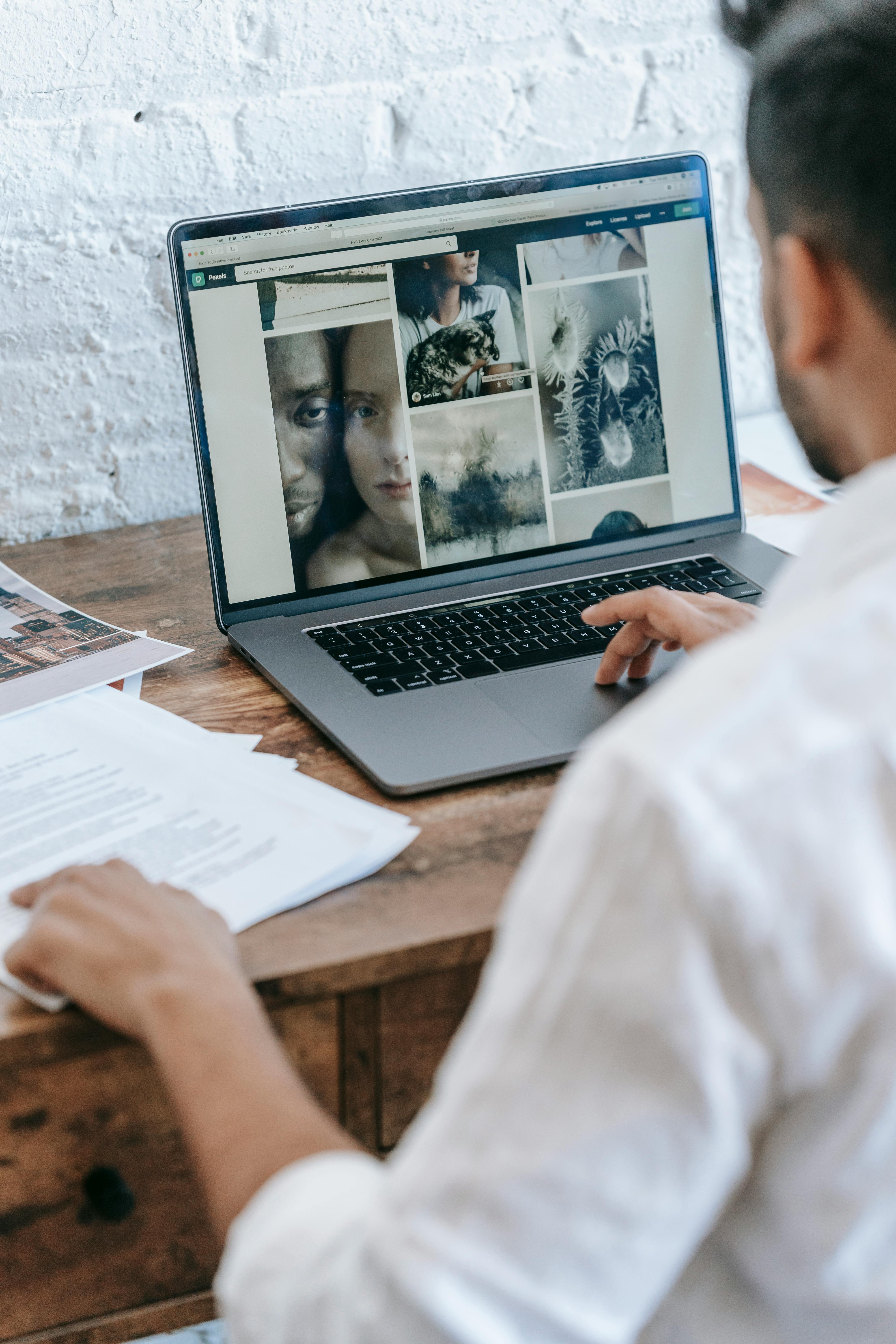 man sitting at table and working on laptop in light room