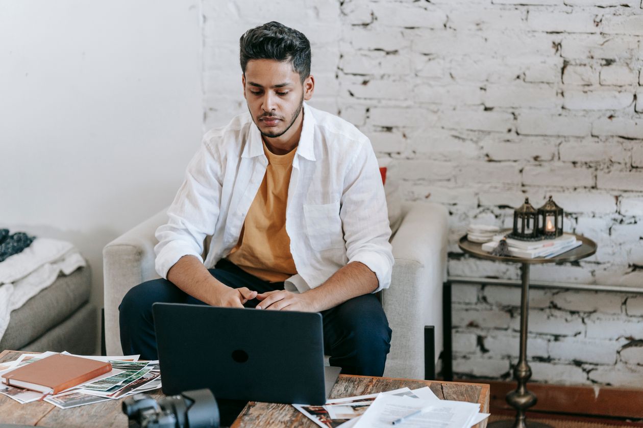 Photographer working at a table with a camera, printed photos and a laptop in a studio