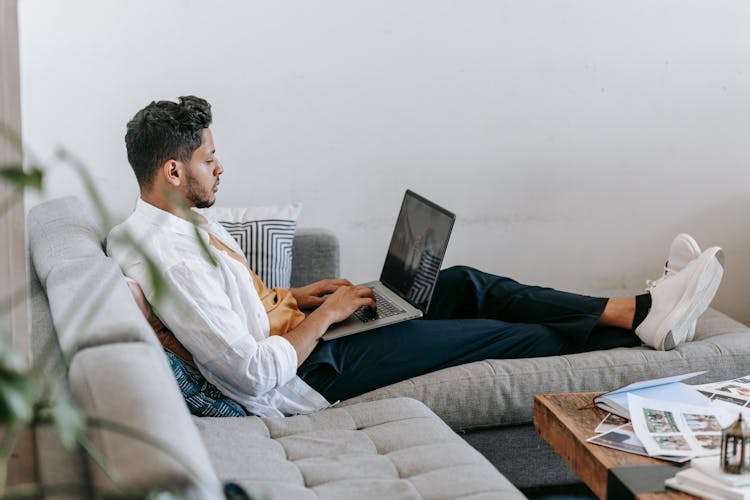 Young Man Working On Laptop On Sofa