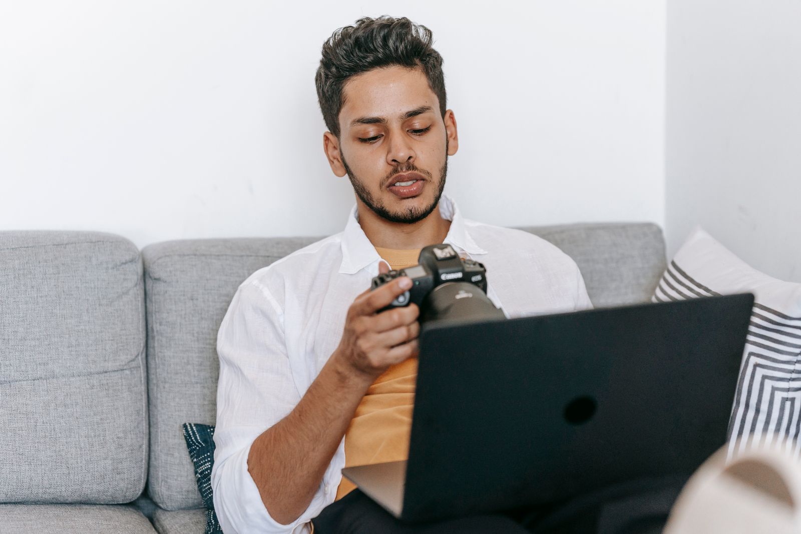 Photographer reviewing images on a laptop and camera while working on a freelance project, the kind of workflow moment where metadata decisions get made before a Marketplace upload