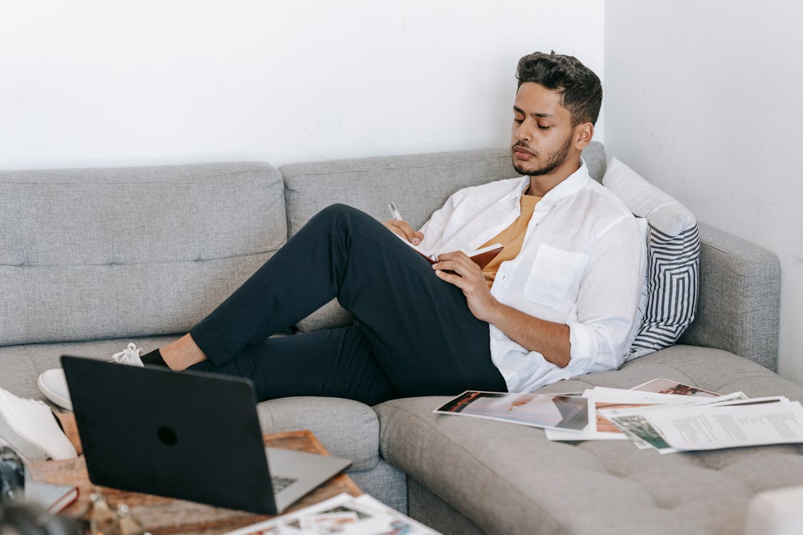Man taking notes in notebook near laptop · Free Stock Photo