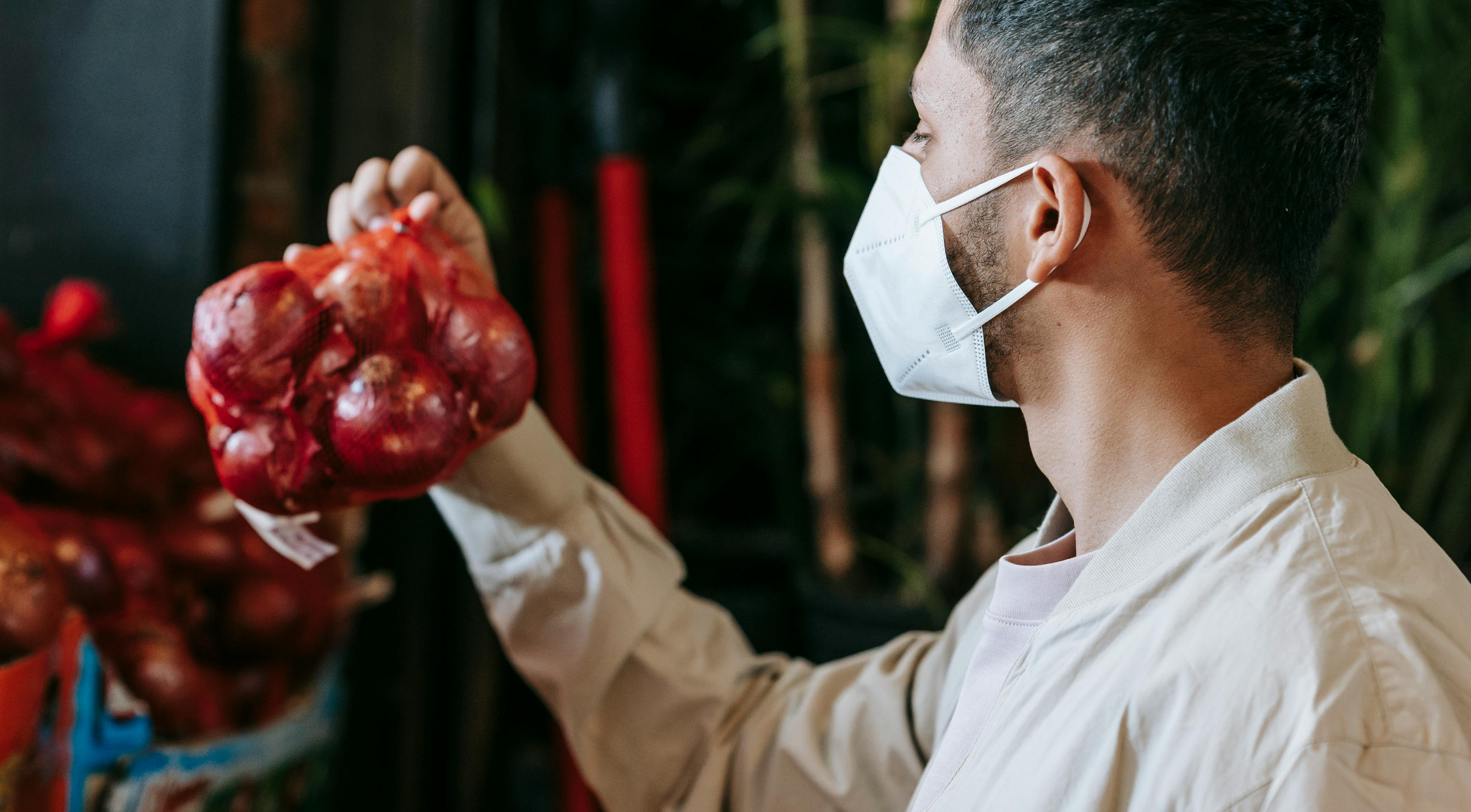 man in mask choosing grocery in store