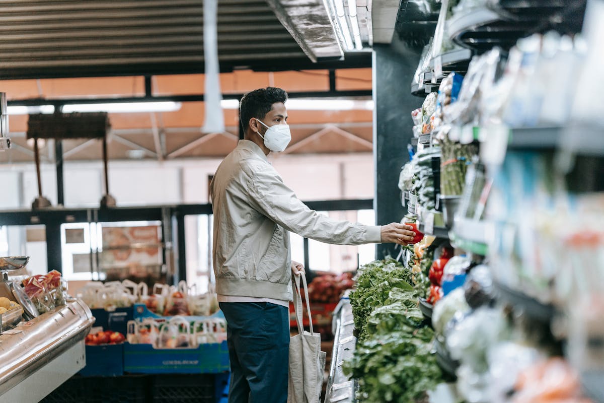 Man in mask choosing fresh groceries in store
