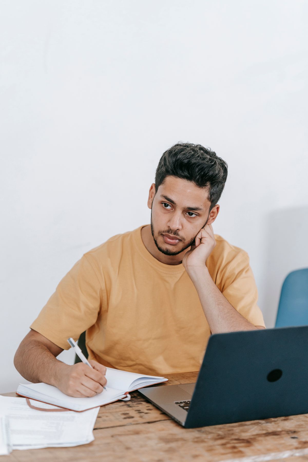 Thoughtful entrepreneur writing notes at a laptop representing careful program vetting to avoid common GLP-1 affiliate mistakes