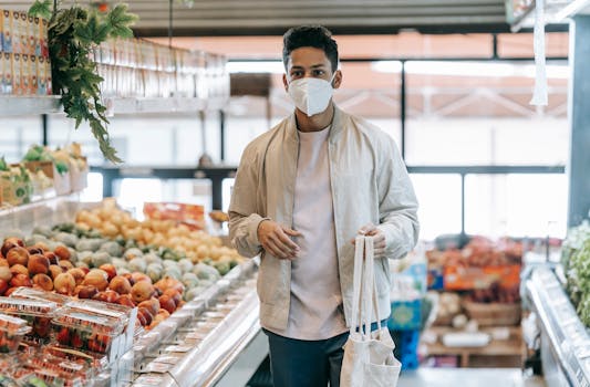 Young man wearing mask shopping in grocery store with eco-friendly bag.