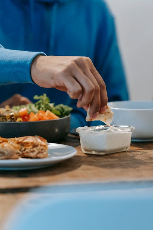 Unrecognizable man dipping flatbread into sauce