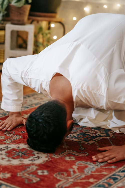Free Man in White Thobe Bowing Down on Red and Blue Rug Stock Photo
