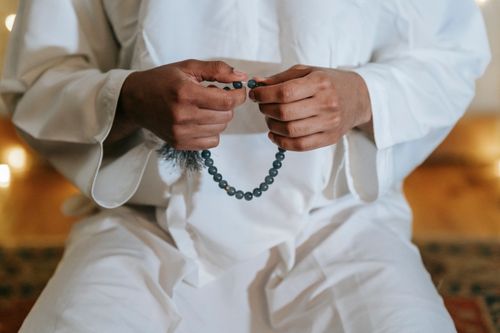 Free A person in traditional wear holding prayer beads, signifying devotion and spirituality. Stock Photo