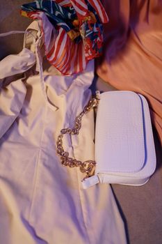 Stylish composition of a chain strap purse and colorful scarf on a dress.