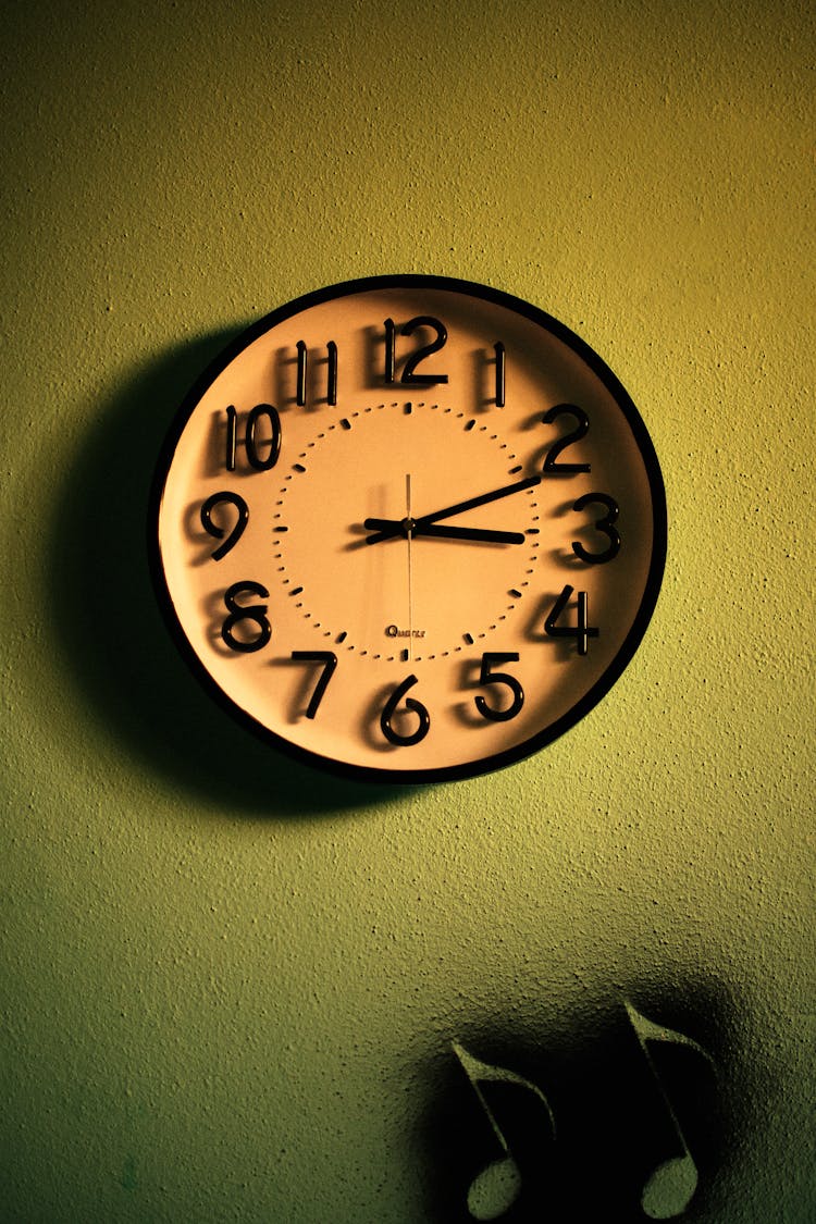 Round Clock Hanging On Green Wall