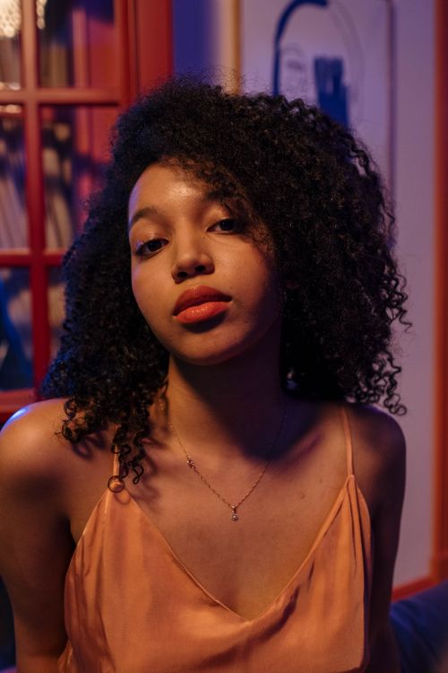 Free Elegant portrait of a woman with curly hair wearing a brown top, captured indoors. Stock Photo