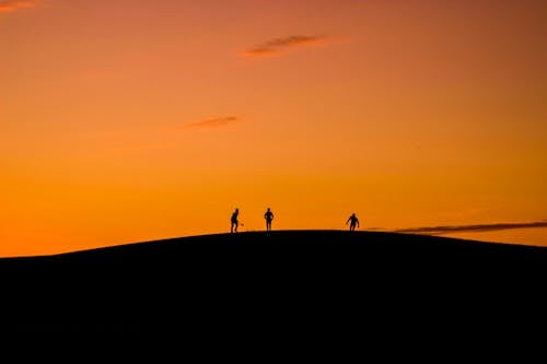Kostenlos Schattenbild Von 3 Personen Im Hügel Während Des Sonnenuntergangs Stock-Foto