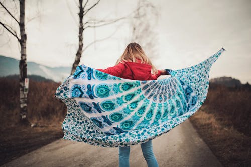Женщина, стоящая посреди дороги с одеялом