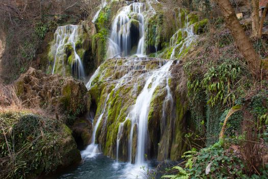 Moss-covered rocks and cascading waterfall in a tranquil forest setting.